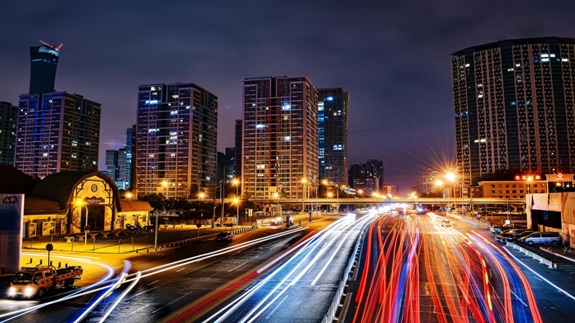 Escena urbana por la noche con luces rojas y blancas de automóviles en una calle concurrida